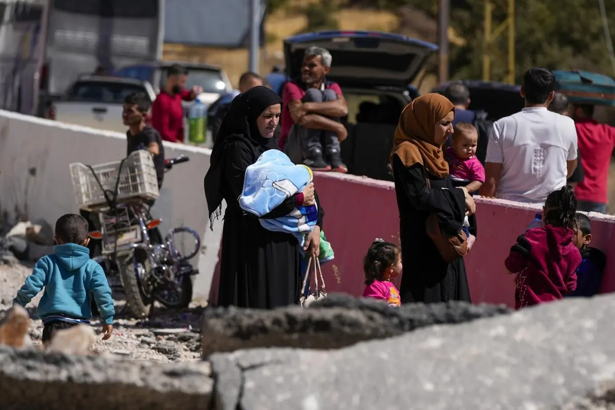 Le persone trasportano i loro bagagli mentre attraversano la Siria a piedi, attraverso un cratere causato dagli attacchi aerei israeliani che mirano a bloccare l\\'autostrada Beirut-Damasco al valico di Masnaa, nella valle orientale della Bekaa, in Libano