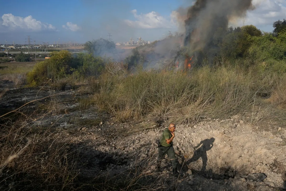 A police officer inspects the area around a fire after the military said it fired interceptors at a missile launched from Yemen that landed in central Israel on Sunday, Sept. 15, 2024. (AP Photo/Ohad Zwigenberg) , APN