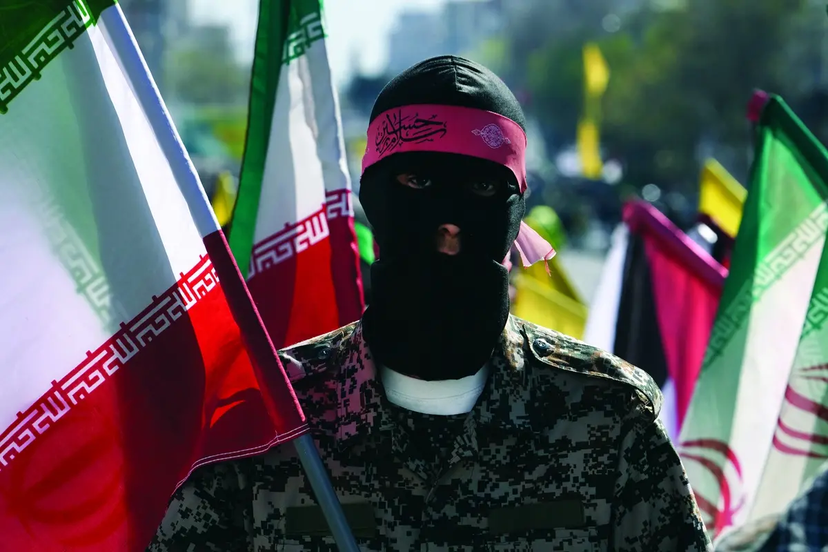 A member of the Iranian paramilitary Basij force holds an Iranian flag as he covers her face in the Palestinian and Lebanese militants style in an annual rally to mark Quds Day, or Jerusalem Day, to support the Palestinians in Tehran, Iran, Friday, April 5, 2024. In the rally in Tehran, thousands attended a funeral procession for the seven Revolutionary Guard members killed in an airstrike widely attributed to Israel that destroyed Iran\\'s Consulate in the Syrian capital on Monday. (AP Photo/Vahid Salemi) , APN