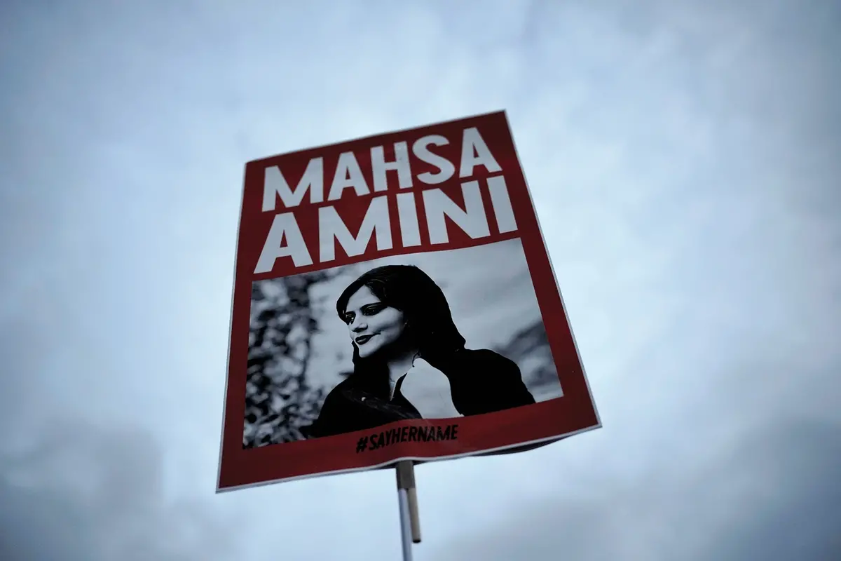 FILE - A woman holds a placard with a picture of Iranian woman Mahsa Amini during a protest against her death, in Berlin, Germany, on Sept. 28, 2022. Iran is responsible for the \"physical violence\" that led to the death of Mahsa Amini in September 2022 and sparked nationwide protests against the country\\'s mandatory headscarf, or hijab, laws and its ruling theocracy, a U.N. fact-finding mission said Friday, March 8, 2024. (AP Photo/Markus Schreiber, File) , AP