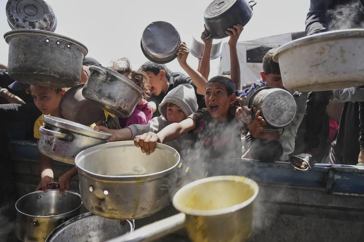 Palestinian children struggle to get donated food at a community kitchen in Khan Younis, Gaza Strip, Saturday, May 3, 2025. (AP Photo/Abdel Kareem Hana) , APN