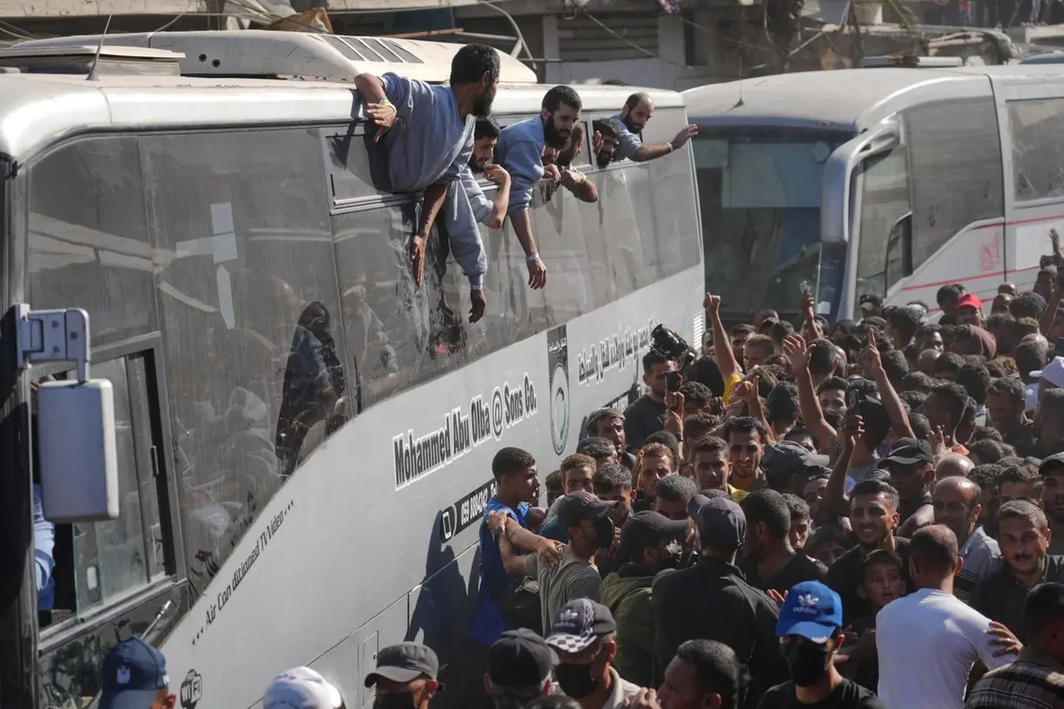 People gather to greet freed Palestinian prisoners arriving on buses in the Gaza Strip after their release from Israeli jails under a ceasefire agreement between Hamas and Israel, outside Nasser Hospital in Khan Younis, southern Gaza Strip, Monday, Oct. 13, 2025. (AP Photo/Jehad Alshrafi)