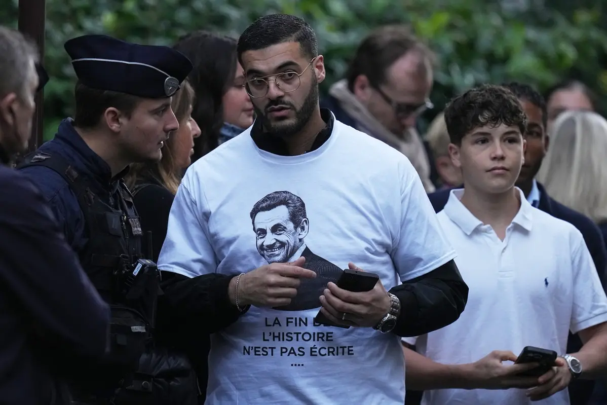 A man wears a t-shirt in a show of support for Nicolas Sarkozy during a rally outside former French President Nicolas Sarkozy's home, Tuesday, Oct. 21, 2025 in Paris as former French President Nicolas Sarkozy heads to prison to serve time for a criminal conspiracy to finance his 2007 election campaign with funds from Libya. (AP Photo/Thibault Camus) Associated Press / LaPresseOnly italy and spain