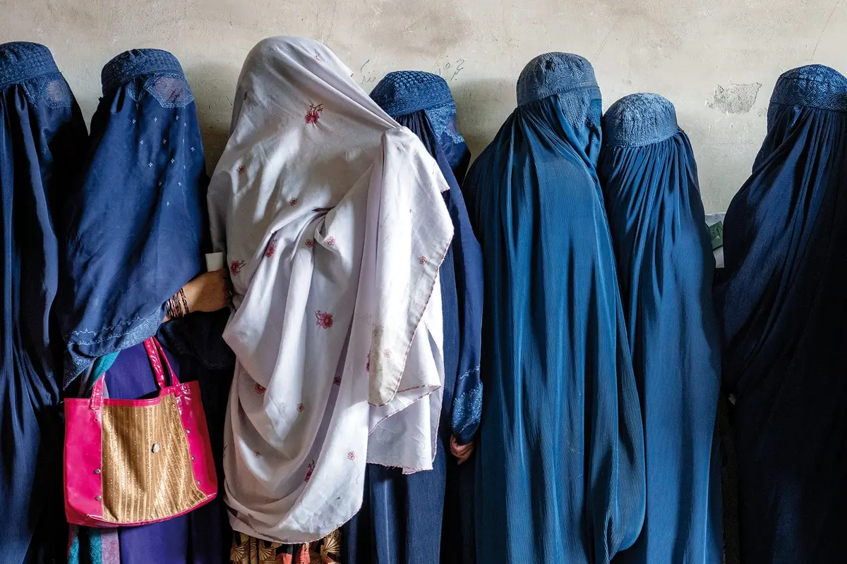 FILE - Afghan women wait to receive food rations distributed by a humanitarian aid group, in Kabul, Afghanistan, on May 23, 2023. Afghan women feel scared or unsafe leaving their home alone because of Taliban decrees and enforcement campaigns on clothing and male guardians, according to a report from the U.N. mission in Afghanistan. (AP Photo/Ebrahim Noroozi, File) , AP