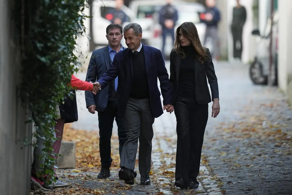 Former French President Nicolas Sarkozy shakes hands as he and his wife Carla Bruni-Sarkozy leave their home Tuesday, Oct. 21, 2025 in Paris as Nicolas Sarkozy heads to prison to serve time for a criminal conspiracy to finance his 2007 election campaign with funds from Libya. (AP Photo/Thibault Camus) Associated Press / LaPresse Only italy and spain , APN
