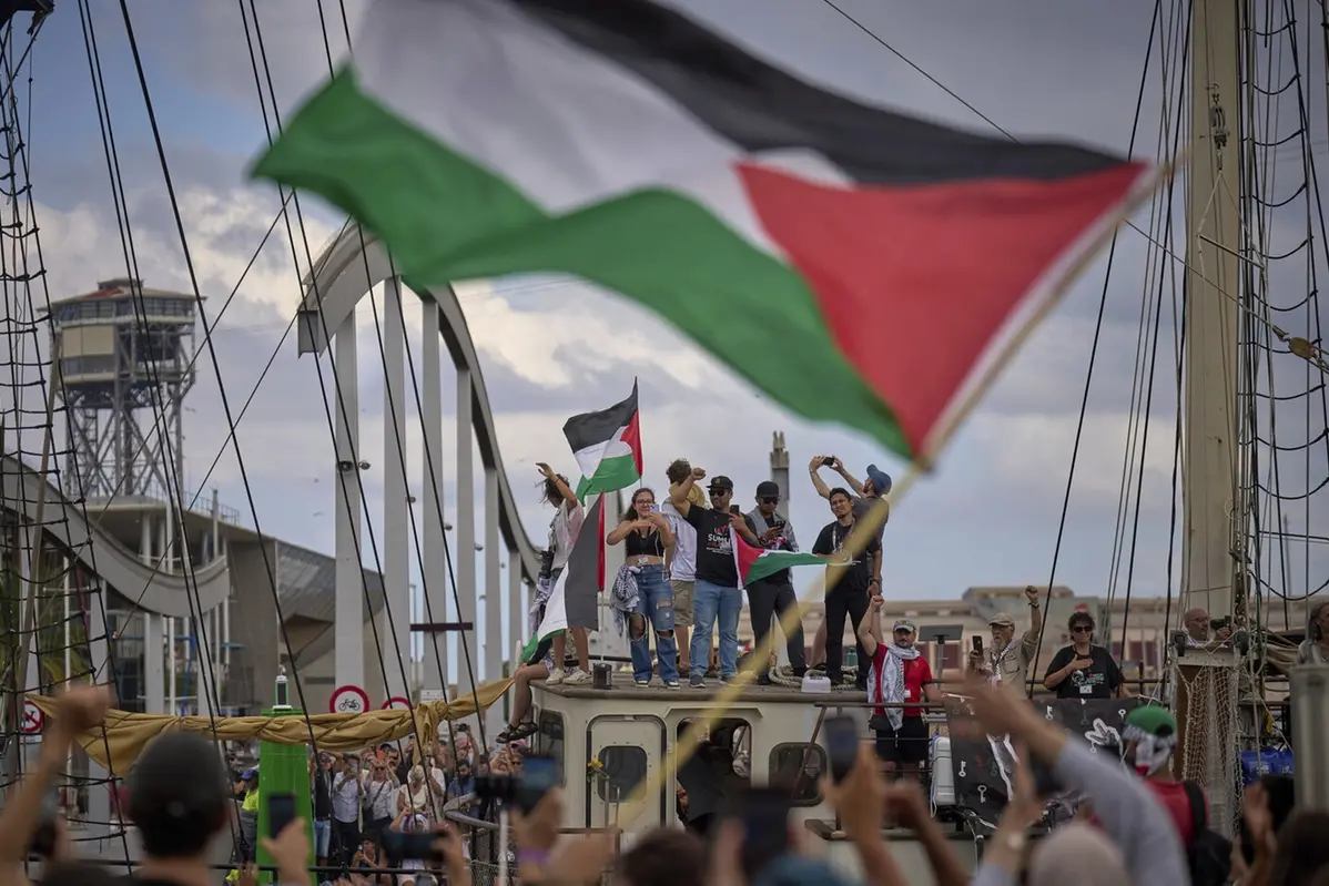 Activists wave on a boat taking part in a civilian flotilla bound for Gaza, aiming to break the Israeli blockade and deliver humanitarian aid, in Barcelona, Spain, Sunday, Aug. 31, 2025. (AP Photo/Emilio Morenatti) , APN
