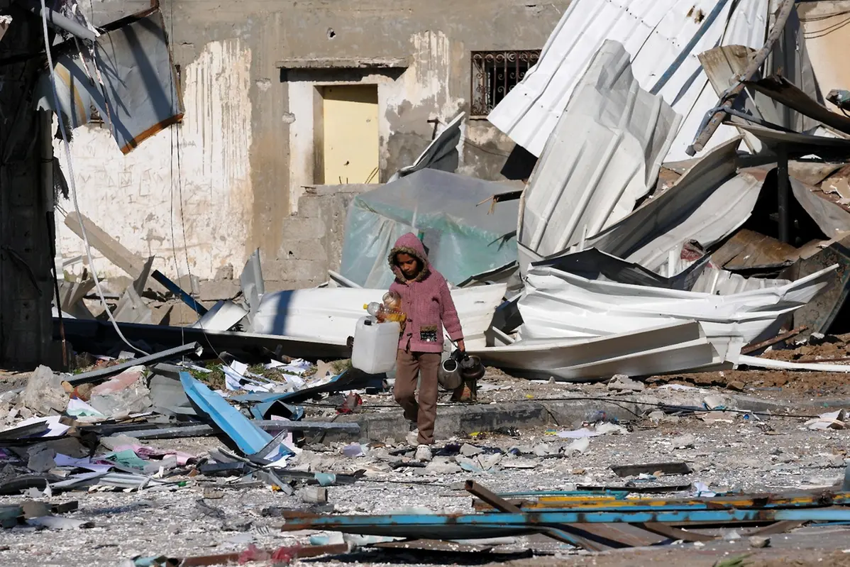 A Palestinian child walks past factories destroyed in the Israeli bombardment of the Gaza Strip in Deir al Balah on Saturday, Jan. 13, 2024. (AP Photo/Adel Hana) , Associated Press/LaPresse