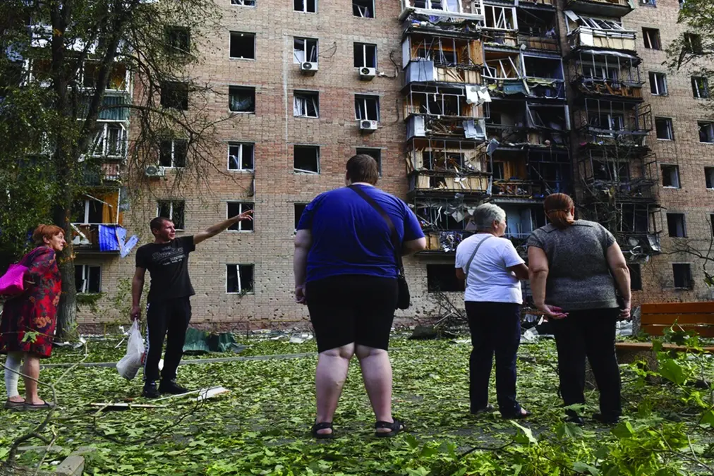 Residents of an apartment building damaged after shelling by the Ukrainian side stand near the building in Kursk, Russia, Sunday, Aug. 11, 2024. (AP Photo)