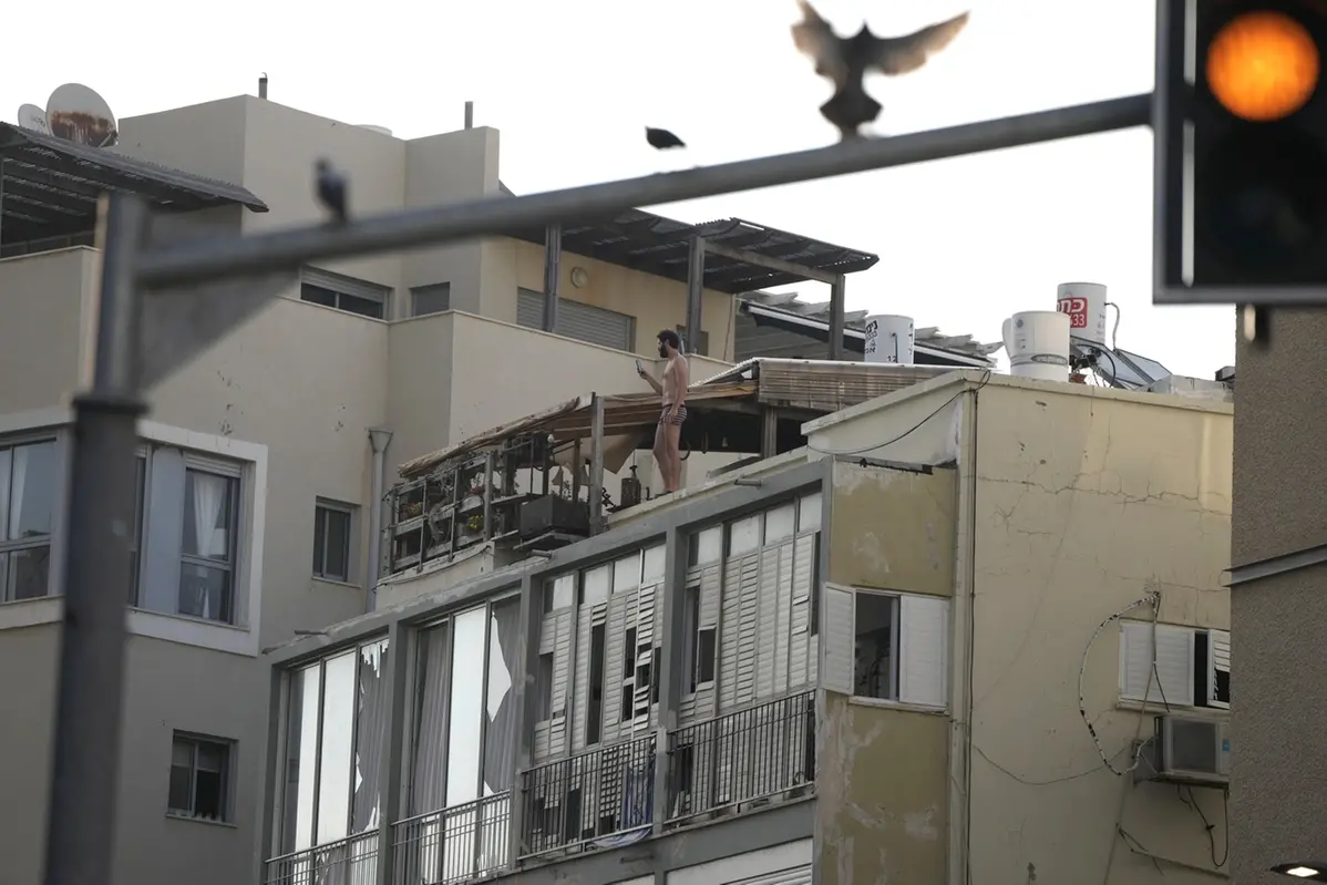 A man films the scene of a deadly explosion, from his rooftop in Tel Aviv, Israel, Friday, July 19, 2024. (AP Photo/Oded Balilty) , APN